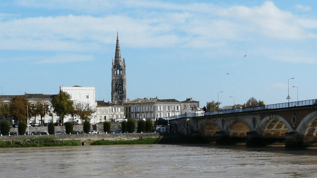Pont de pierre et clocher de l’église Saint-Jean-Baptiste à Libourne, vue depuis les rives de la Dordogne lors d’une escapade en train depuis Bordeaux.